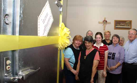 Some of the volunteers gather by the new walk-in freezer, wrapped in yellow ribbon.